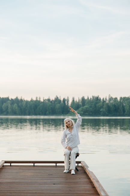 Woman practicing yoga at sunrise on a wooden dock